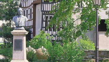 Grüne Umgebung mit Statue und traditionellem deutschen Architektur