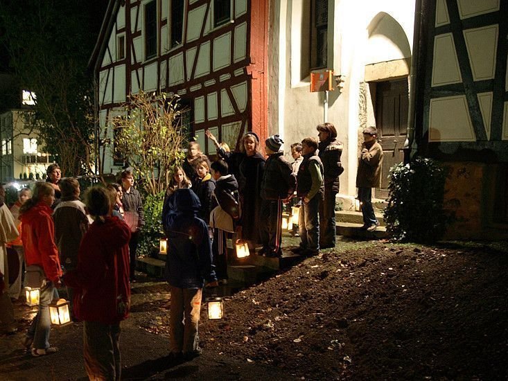 Menschen versammeln sich bei Nacht vor einem historischen Gebäude mit Laternen