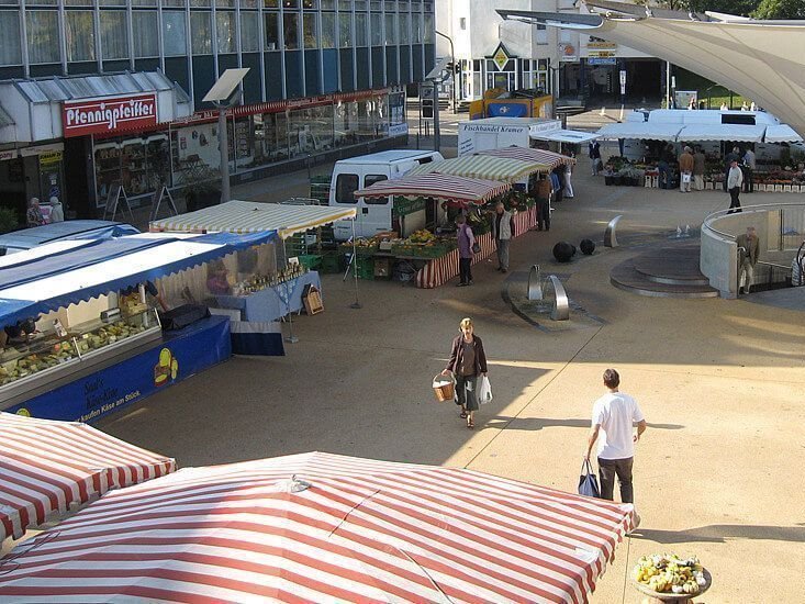 Blick auf einen Marktplatz mit Verkaufsständen und Passanten