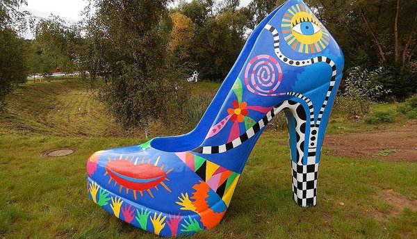 Kunstvolle, bunte Skulptur eines hohen Damenschuhs in der Natur.