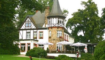 Historisches Gebäude mit begrünten Außenanlagen und Terrasse