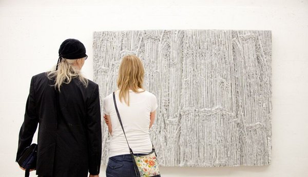 Zwei Personen in einer Kunstgalerie beobachten ein abstraktes Kunstwerk