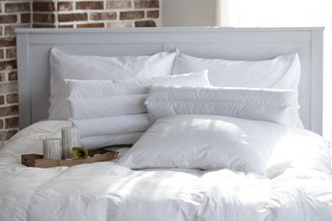 Gemütliches Bett mit weißen Kissen und einem Tablett auf der Bettdecke
