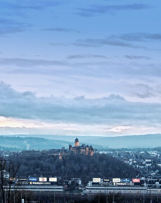 Blick auf eine Stadt mit Hügeln und Wolken am Himmel