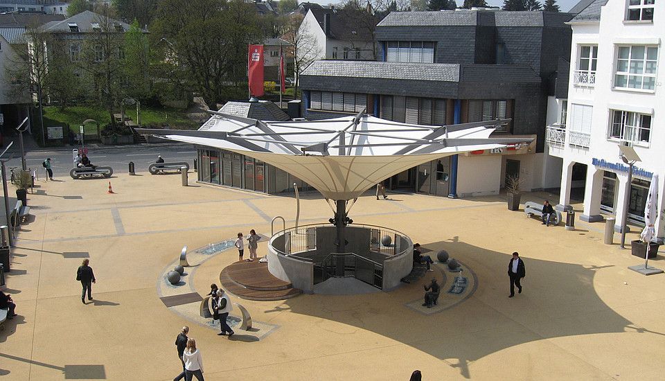 Ein öffentlicher Platz mit einem modernen Pavillon und Besuchern