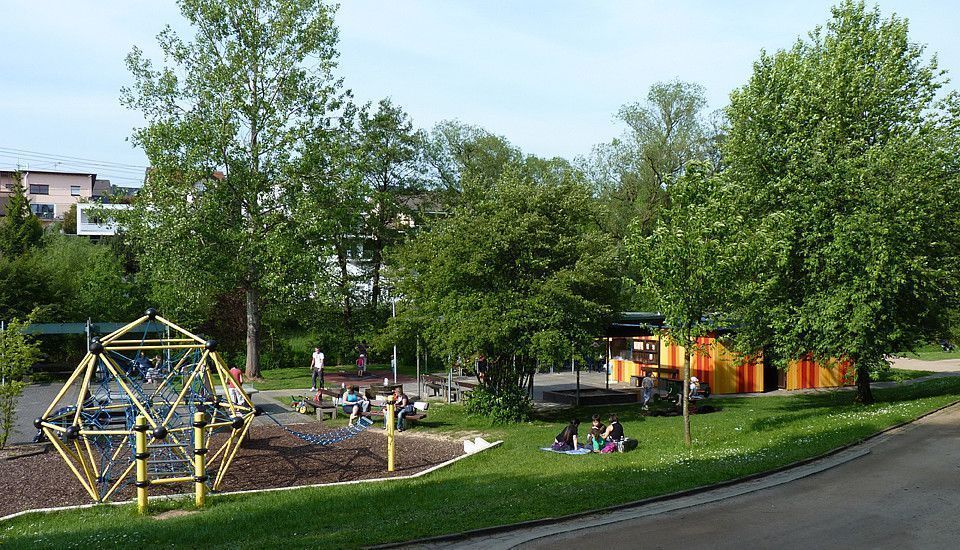 Grüne Landschaft mit Spielplatz und Gruppen von Jugendlichen auf dem Rasen