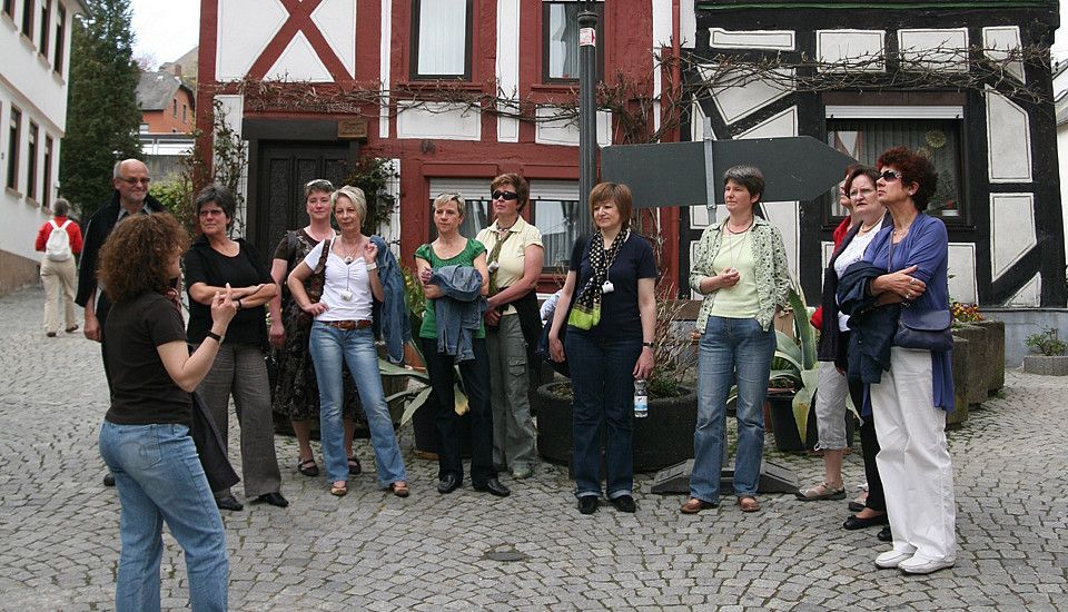 Eine Gruppe von Menschen hört einer Rednerin in der Stadt zu
