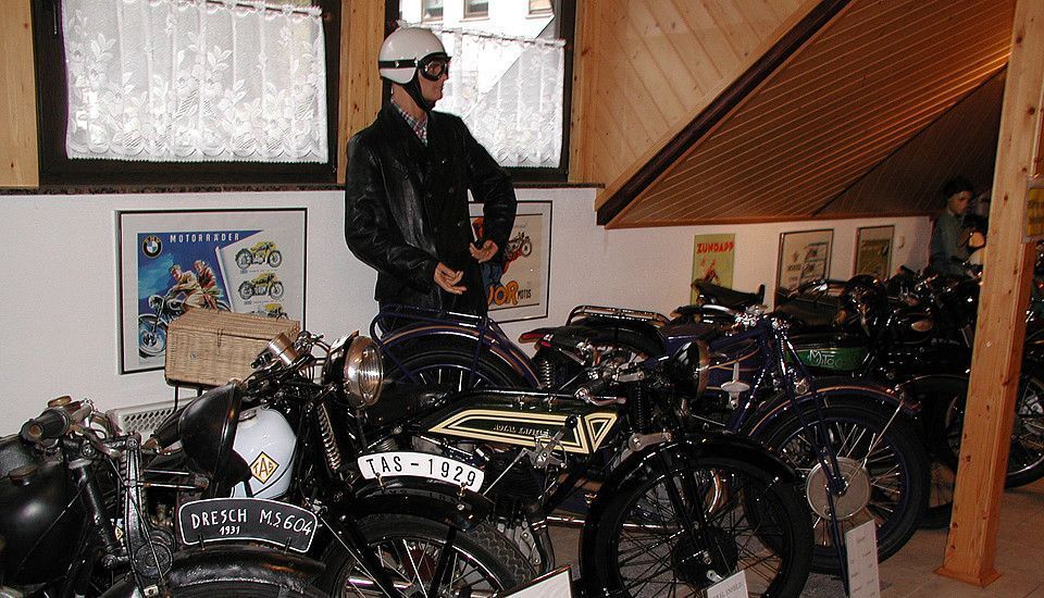 Verschiedene alte Motorräder und eine Figur in einer Ausstellung