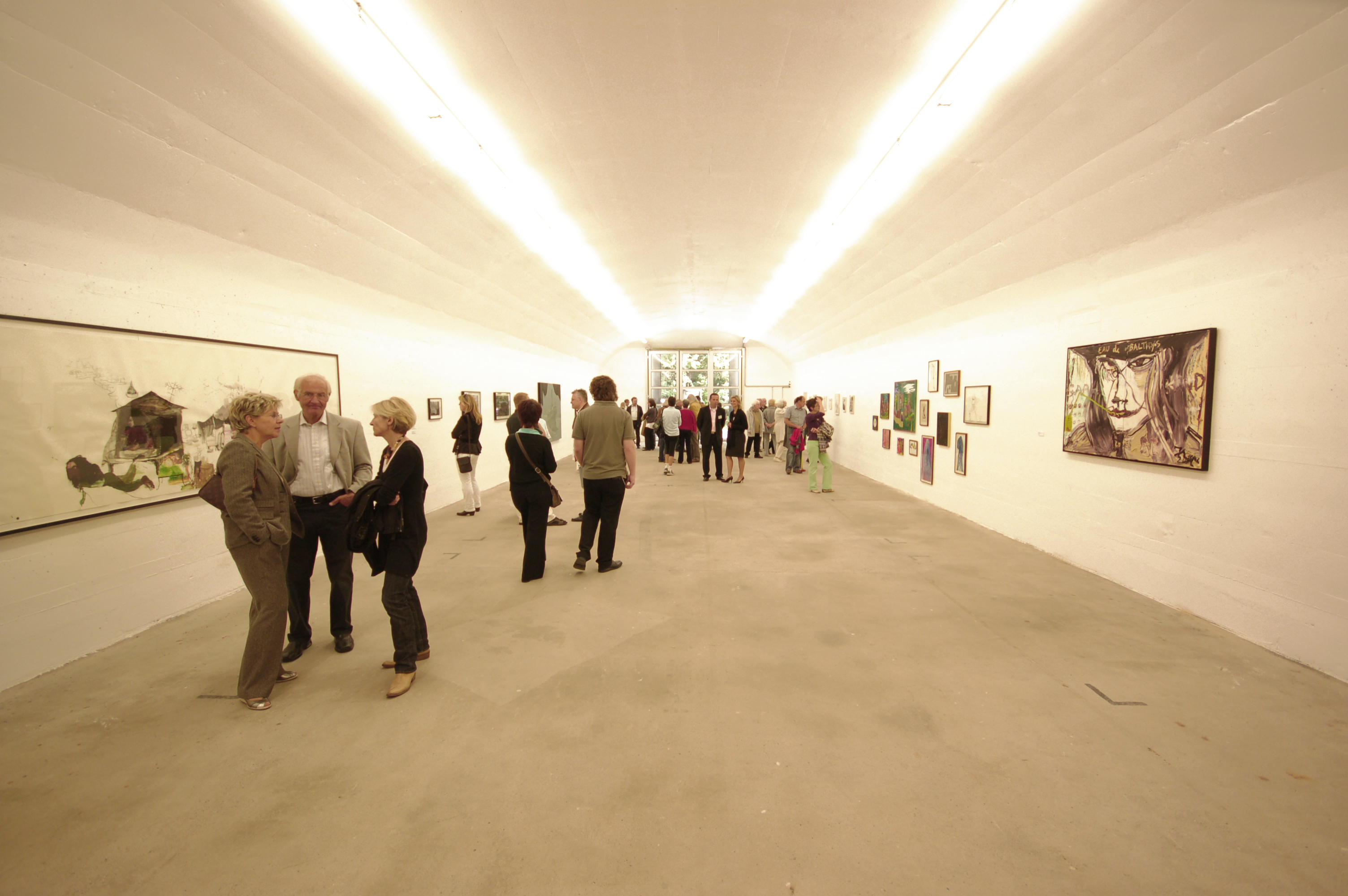 Besucher betrachten Kunstwerke in einer Galerie mit heller Beleuchtung