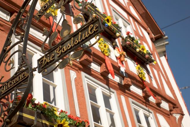Detailansicht des Schildes 'Die Gaststube' an einer historischen Fassade