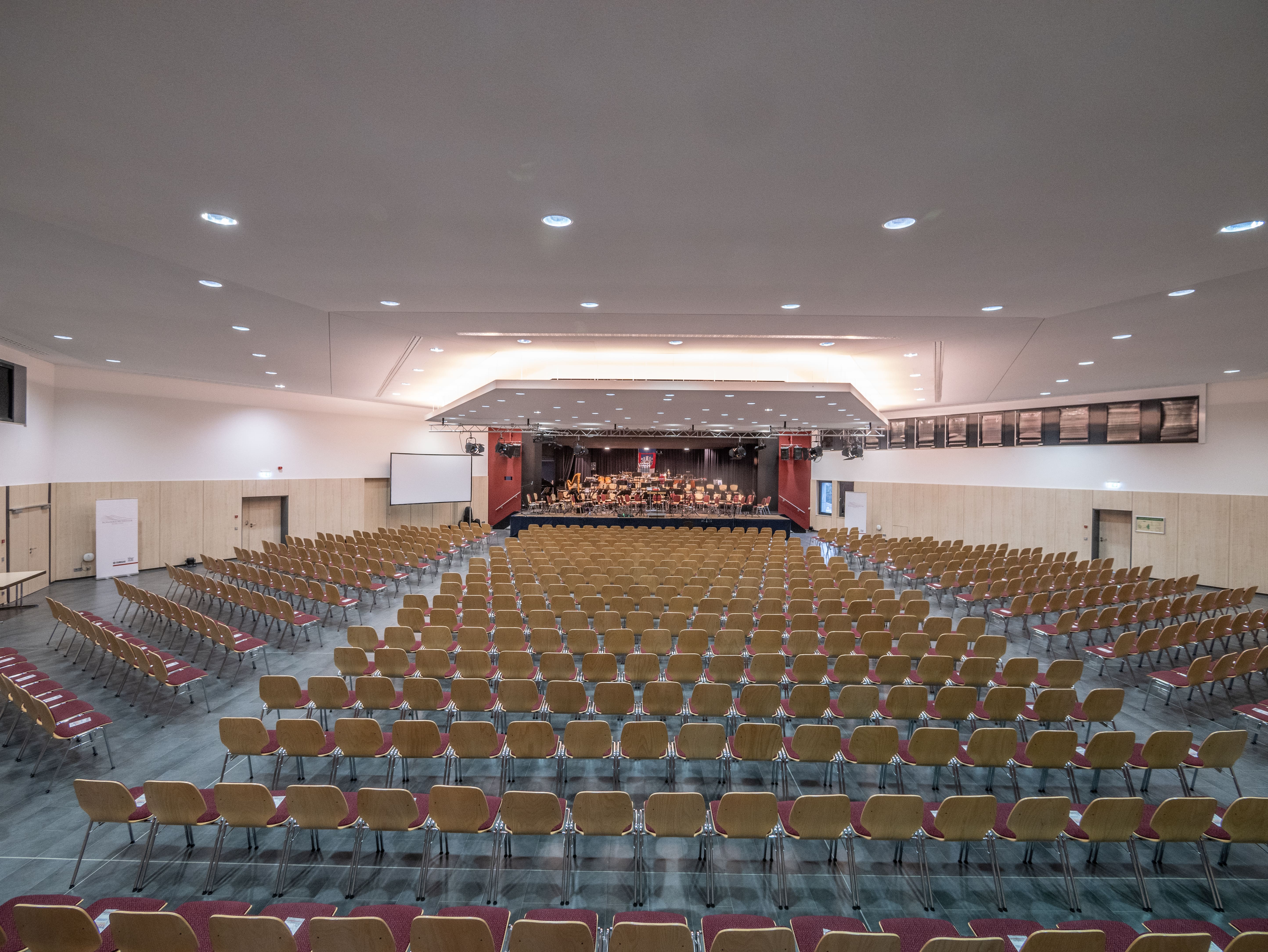 Blick auf eine große Halle mit Reihen von leeren Stühlen und Bühne