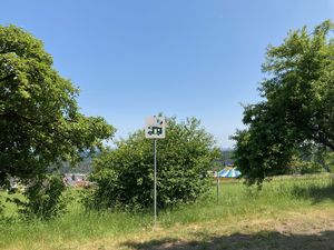 Ein Hinweiszeichen steht zwischen Bäumen auf einer Wiese